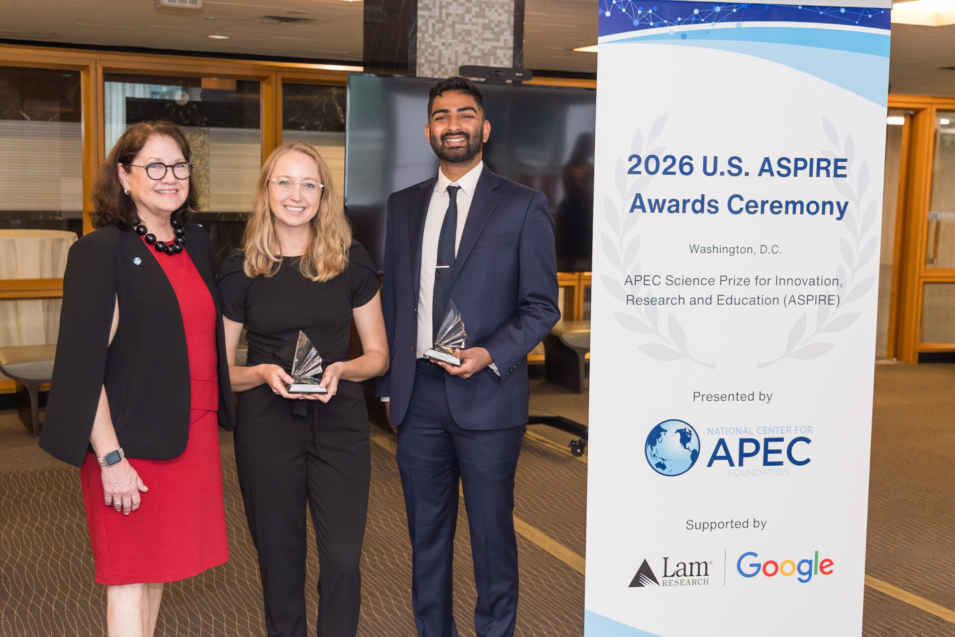 Three award recipients posing with trophies beside a tall ASPIRE Awards banner at a ceremony in Washington, DC.